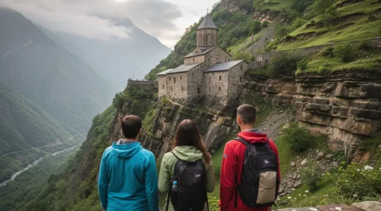 Petit groupe de voyageurs admirant un monastère arménien perché dans les montagnes du Caucase